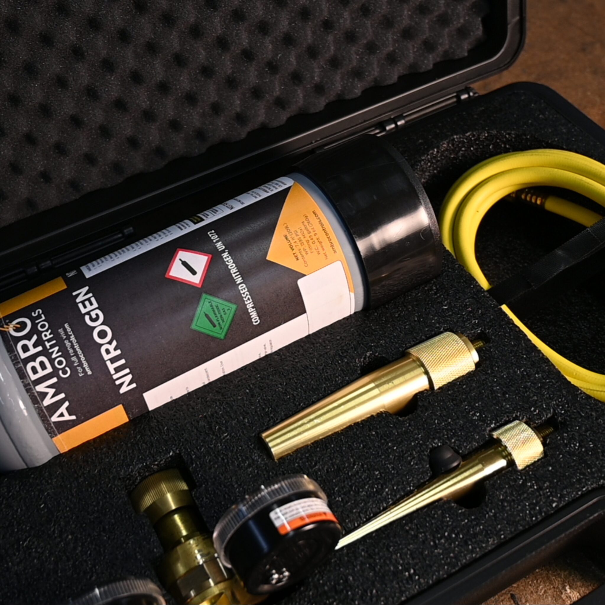 Close-up of a nitrogen purging kit inside a foam-lined carrying case, including a compressed nitrogen cylinder, brass nozzles, a dual-gauge regulator, and a yellow hose.