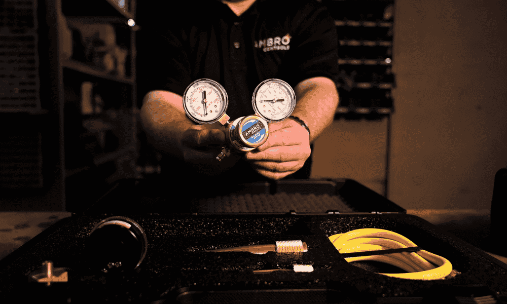 This image shows a technician holding a nitrogen regulator with dual pressure gauges, part of a tool kit. It likely represents the Nitrogen Regulator category for a website.